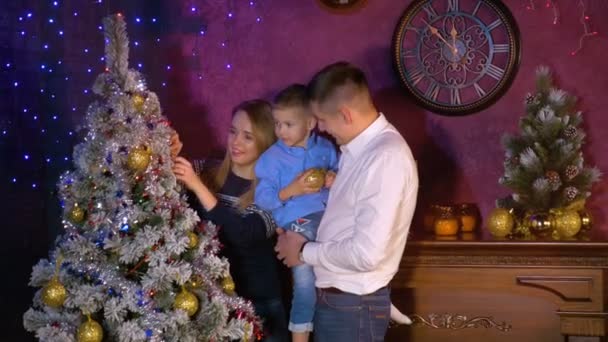 Uma família examina e tira bugigangas da árvore de Natal . — Vídeo de Stock