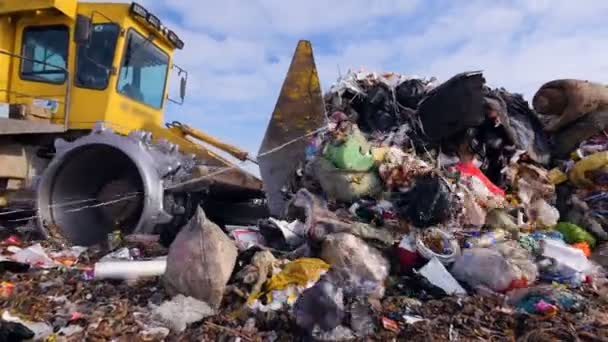 Enviromet pollution concept. A low angle view on a landfill compactor moving trash. — Stock Video