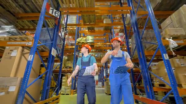 Vue à angle bas sur deux hommes surveillant l'état d'un entrepôt . — Video