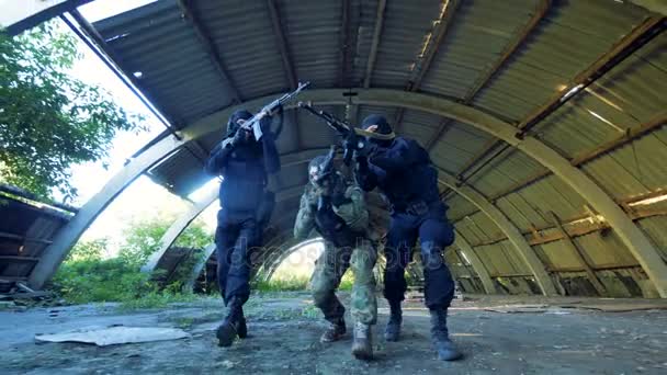Tre oigenkännlig beväpnade män flytta långsamt på marken letar skytte mål. — Stockvideo