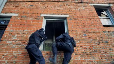 Kırmızı tuğlalı bir pencereden bina modern mühimmat ile iki asker girin.