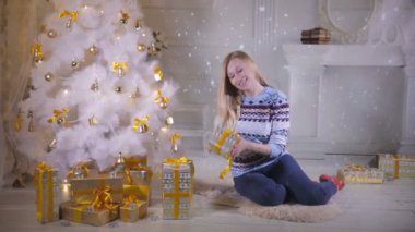 Genç bir kadın sabırsızlıkla Noel hediyelerini sallıyor.