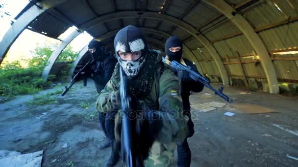 Люди, одетые как террористы с оружием, движущимися вперед к камере. 4K — стоковое видео