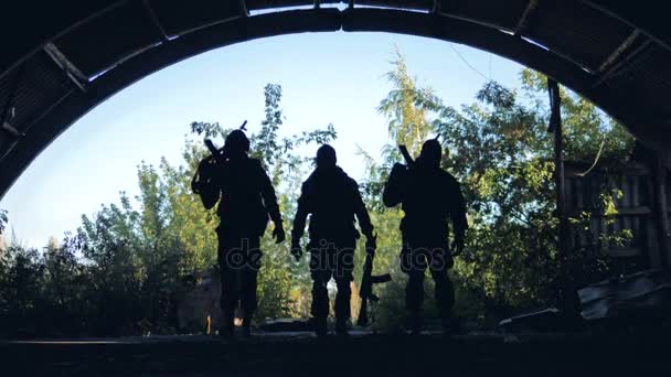 Drie silhouetten van gewapende soldaten naar de camera. — Stockvideo