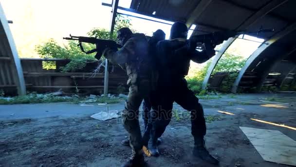 Três homens armados estão num edifício abandonado durante uma operação militar. 4K . — Vídeo de Stock