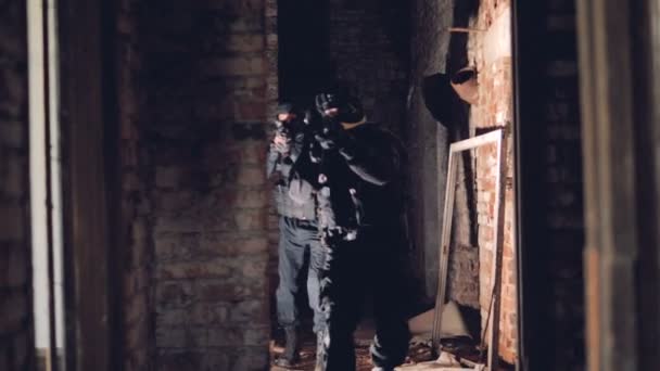 Soldados golpeados con armas caminan dentro de un edificio en ruinas durante la operación de liberación de rehenes. 4K . — Vídeos de Stock