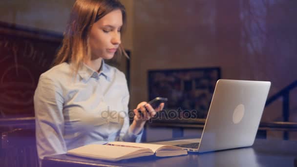 Giovane signora utilizzando computer portatile e smartphone a tarda sera. 4K . — Video Stock