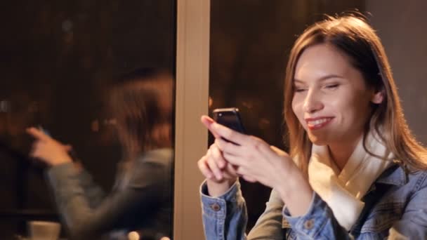 Vacker kvinna textning på smartphone i café. 4k. — Stockvideo