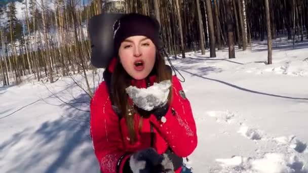 Jovem menina turística feliz sopra a neve das palmas das mãos . — Vídeo de Stock