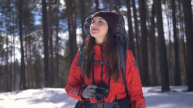 Gülümseyen mutlu genç kadın photocamera kullanarak fotoğraf çekmek kış ormanda hiking.