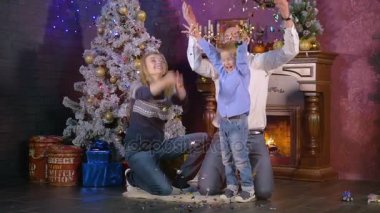 Mutlu aile Noel şömine yakınındaki konfeti atmak. Ağır çekim.