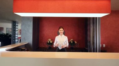 Gülümseyen ve otel lobisinde anahtar kart veren kadın resepsiyonist.