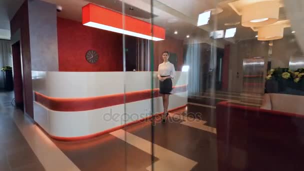 Charming female receptionist in hotel lobby. — Stock Video