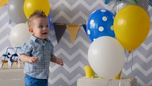 Un niño toca cuidadosamente globos de colores. . — Vídeos de Stock