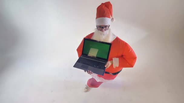 圣诞老人在一个充气西装指向一个礼品笔记本电脑与绿色屏幕. — 图库视频影像