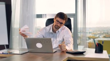 Onun laptop ekranında üzücü bir işadamı bakar.