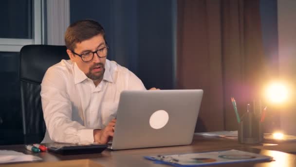 Un hombre de negocios soñoliento trabaja hasta tarde en su portátil . — Vídeo de stock