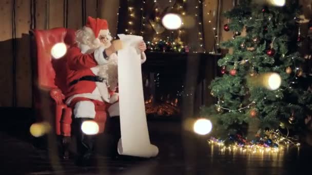 Ein glücklicher Weihnachtsmann steht an Heiligabend auf der Geschenkliste am Kamin. 4k. — Stockvideo