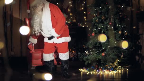 Kedves Santa záradék ül a széke előtt a karácsonyfa. — Stock videók