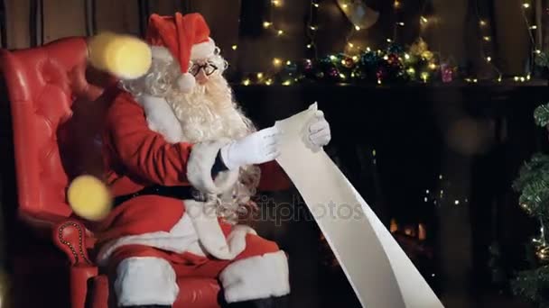 Santa ve svém křesle poblíž vánoční stromeček nový rok dárek seznam k přečtení.
