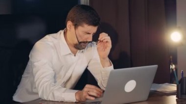 Yorgun bir işadamı türleri ve dinlenmek için gözlüklerini alır.