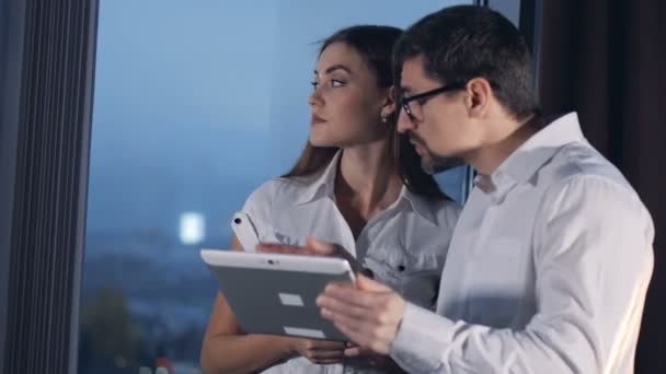 Un hombre de negocios y una mujer de negocios discuten su trabajo mirando una tableta compartida PC. 4K . — Vídeos de Stock