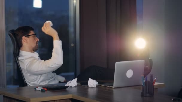 Um homem de negócios entediado joga bolas de papel em frustração . — Vídeo de Stock