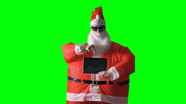 Санта-Клаус на зеленом фоне держит планшетный компьютер . — стоковое видео