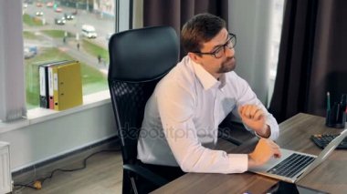 Overworked işadamı kollarını çalışmaları sırasında uzanır..