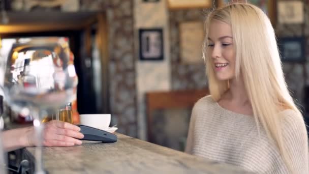Молодая женщина делает бесконтактный платеж и машет кому-то рукой . — стоковое видео