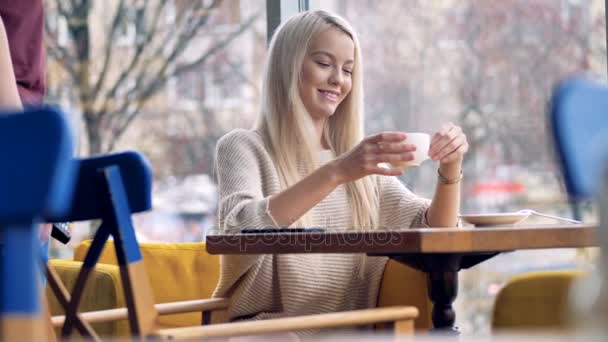 En flicka slutar dricka sitt kaffe för att göra en Nfc-betalning. — Stockvideo