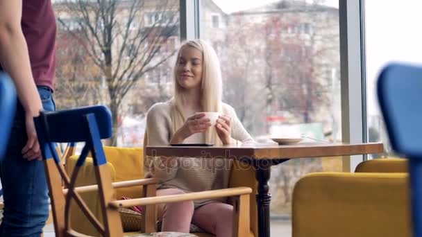 Una chica se sienta en una silla de café y paga por su bebida . — Vídeos de Stock