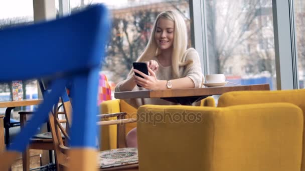 Kobieta wygląda senny w jej ekran smartfona i uśmiecha się. — Wideo stockowe