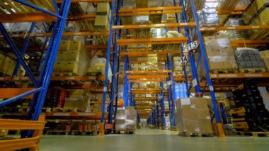 Metal raflar satırları arasında bir uzun ambar koridor.