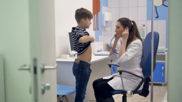 Ein Arzt hört einem Schüler mit Stethoskop zu. — Stockvideo