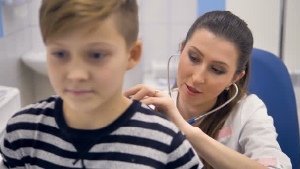 Um close-up de um médico ouvindo os meninos de volta . — Vídeo de Stock