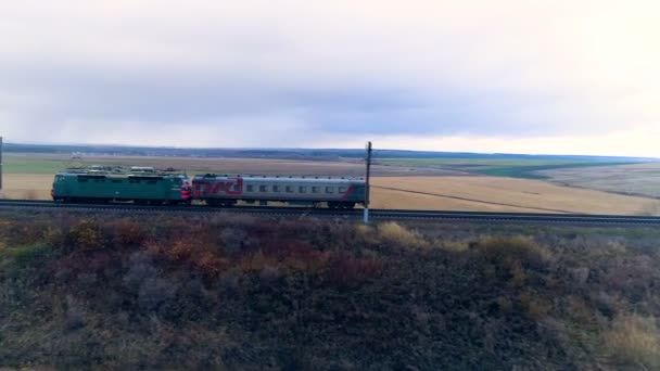 Un coche de motor de trenes se mueve solo con un coche de pasajeros . — Vídeo de stock