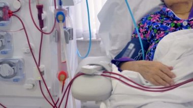 Yaşlı kadının kolunu tüpler tarafından bağlı bir Diyaliz makinesi.