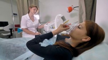 Oksijen maskesi olan bir hastaya bir doktor konuşuyor.