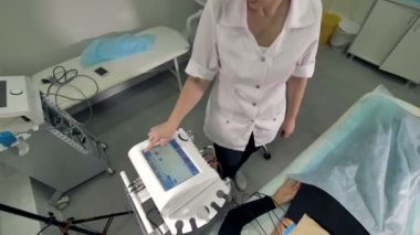Bir doktor bir fizyoterapi cihaz yanında uyuyan bir kadın kurma.