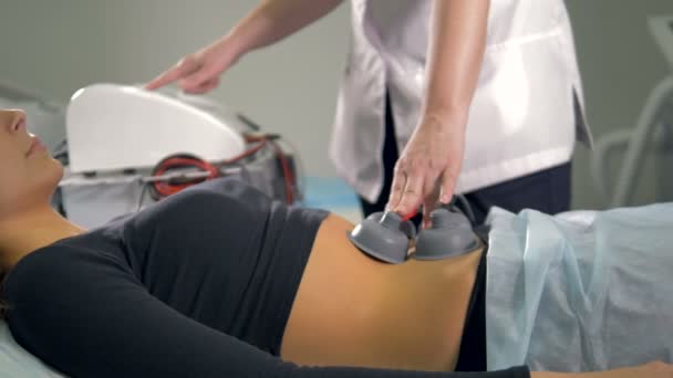 Uma enfermeira médica mantém eletrodos no corpo feminino no lugar . — Vídeo de Stock