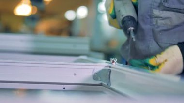 Bir işçi bir Pvc pencere profili üzerinde metal kilit ekler.