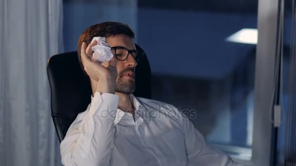Una vista de la cara de un hombre de negocios mientras lanza bolas de papel . — Vídeos de Stock