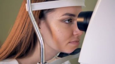 Bir kadın bir görme muayenesi için doktor ofisinde oturur.