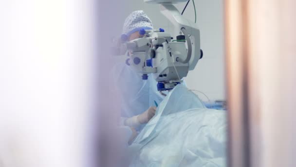Un chirurgo e come assistente sono assorbiti durante un trattamento degli occhi . — Video Stock