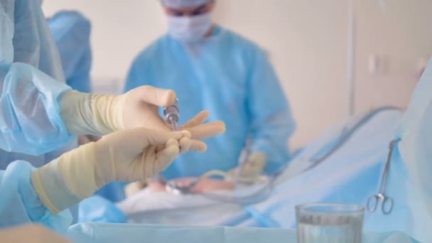 Un assistant va chercher des instruments médicaux à un chirurgien . — Video