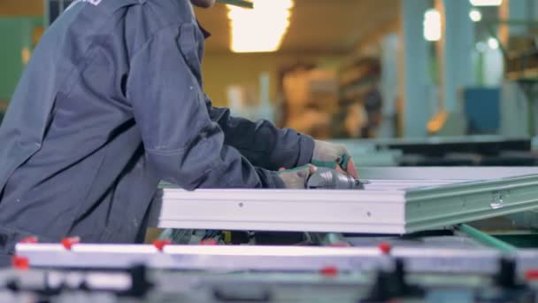 Un taller de ventanas de PVC con un trabajador terminando de añadir accesorios metálicos . — Vídeo de stock