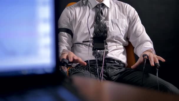 Een computer controleert polygraaf gegevens naast een vergadering man. — Stockvideo