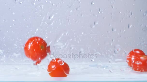 Leckere frische feuchte rote Tomaten, die mit großem Spritzen ins Wasser fallen. Zeitlupe. — Stockvideo