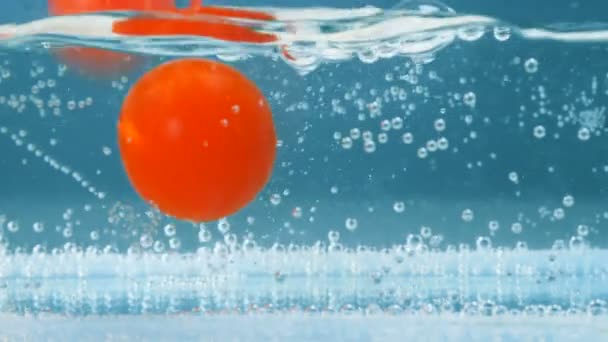 Les tomates rouges éclaboussent dans l'eau douce bleue. Caméra haute vitesse prise . — Video